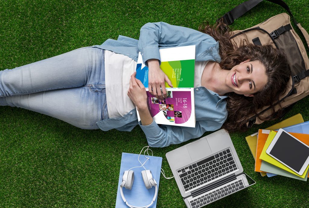 Girl lying on grass with a design book in hand
