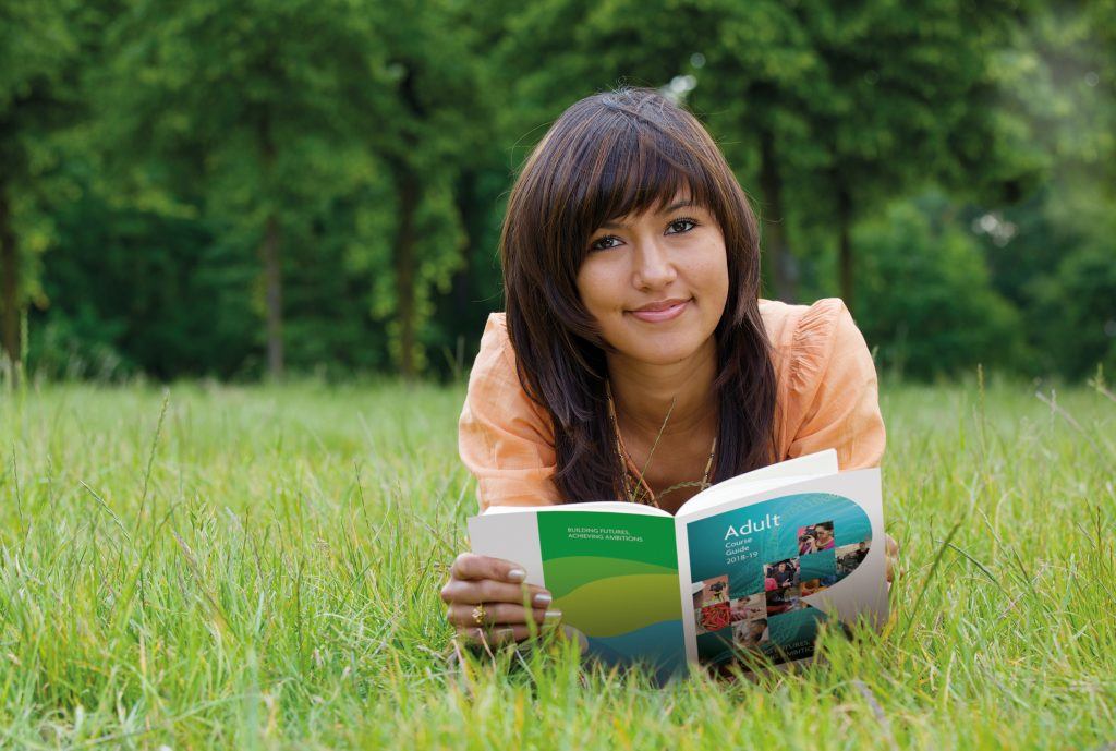 Girl lying on grass reading a brochure